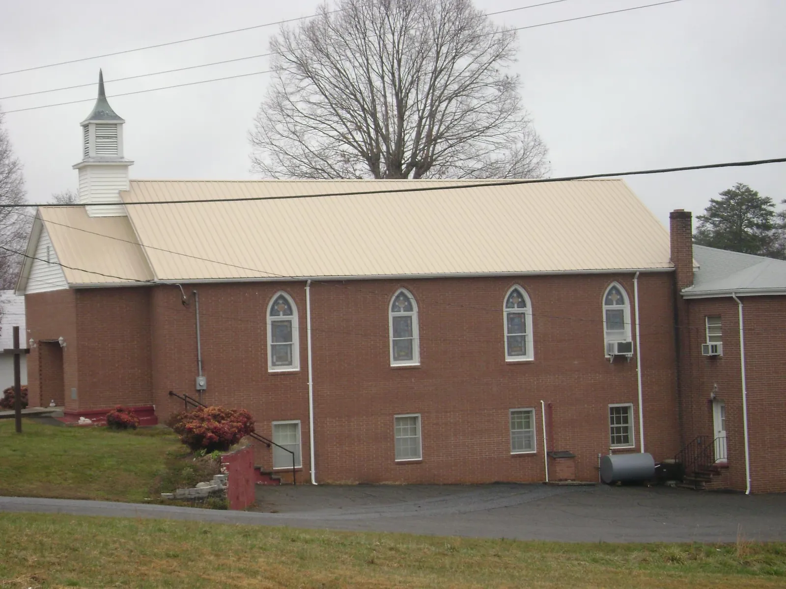 New tan metal roof on a brick church with a white steeple in Hartsdale