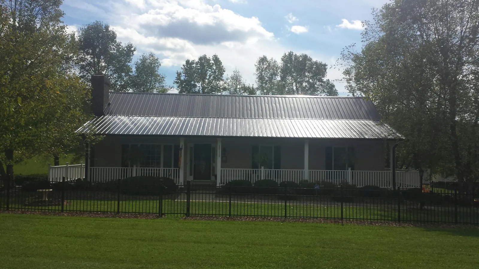 Gray metal roof on a brick ranch with a full width front porch — Gutter Guard Installation work by our crew in Hartsdale
