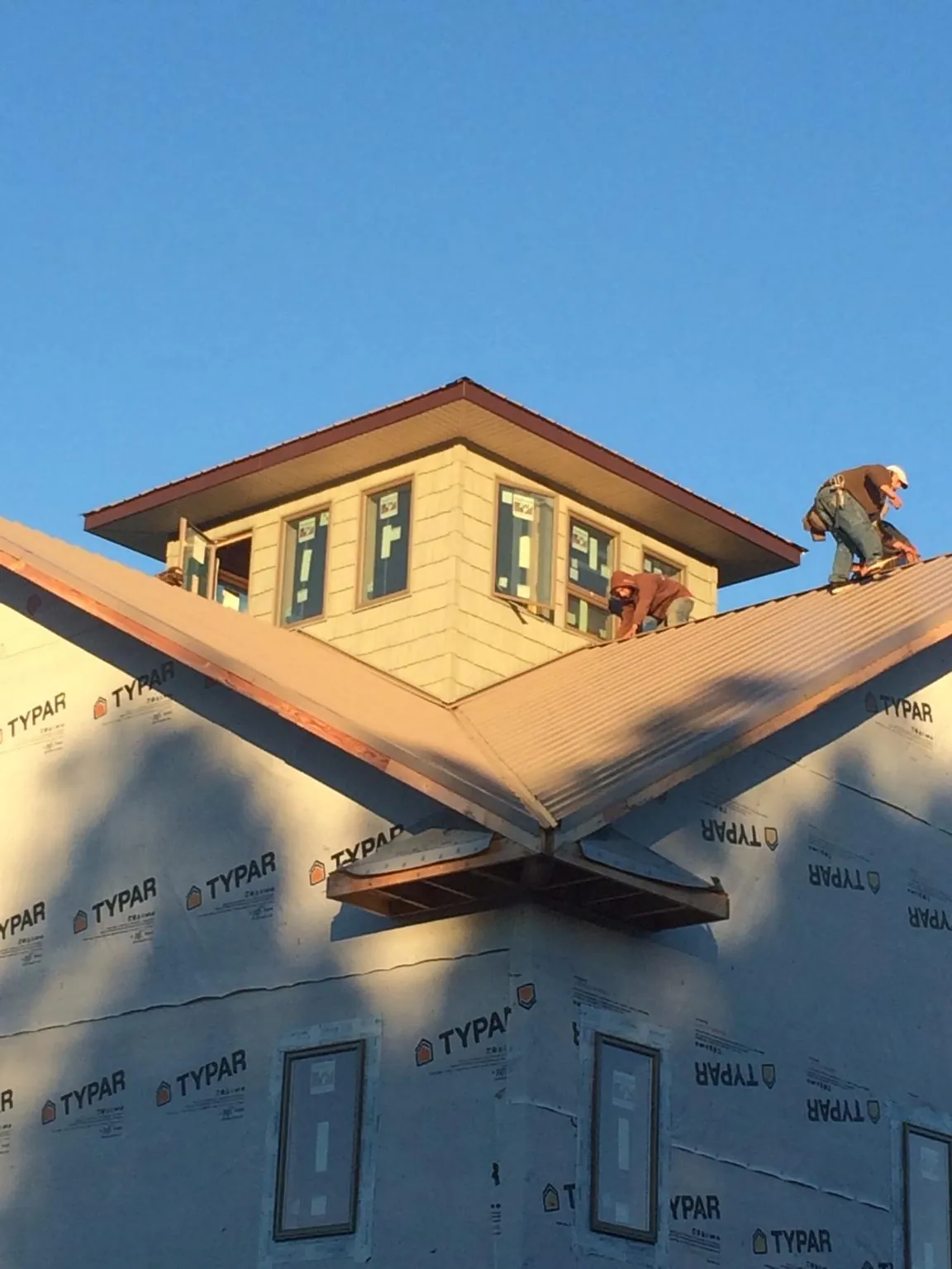 Roofers working around a rooftop cupola on a new metal roof at sunset — Roof Waterproofing in Hartsdale by Roofing Brothers